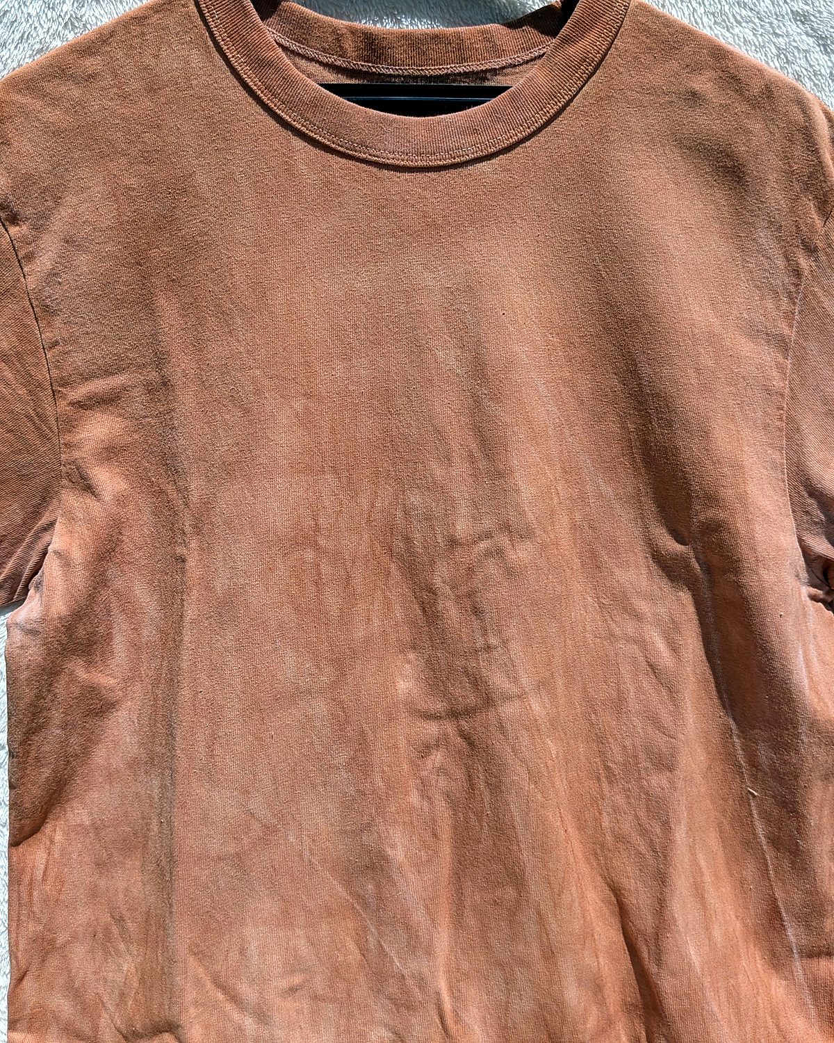 Close-up of a T-shirt hand-dyed with kakishibu, showing the natural mura pattern